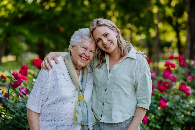 Elderly woman and carer embracing in garden